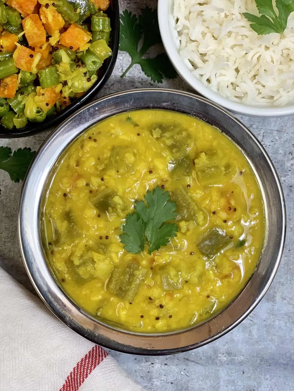 ridge gourd dal served in a bowl with poriyal and rice on the side