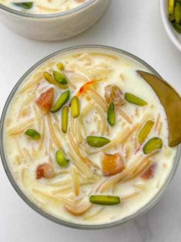 vermicelli kheer (semiya payasam) served in a bowl with a spoon and pista on the side