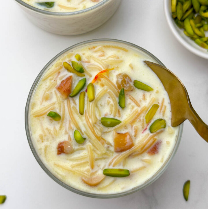 vermicelli kheer (semiya payasam) served in a bowl with a spoon and pista on the side