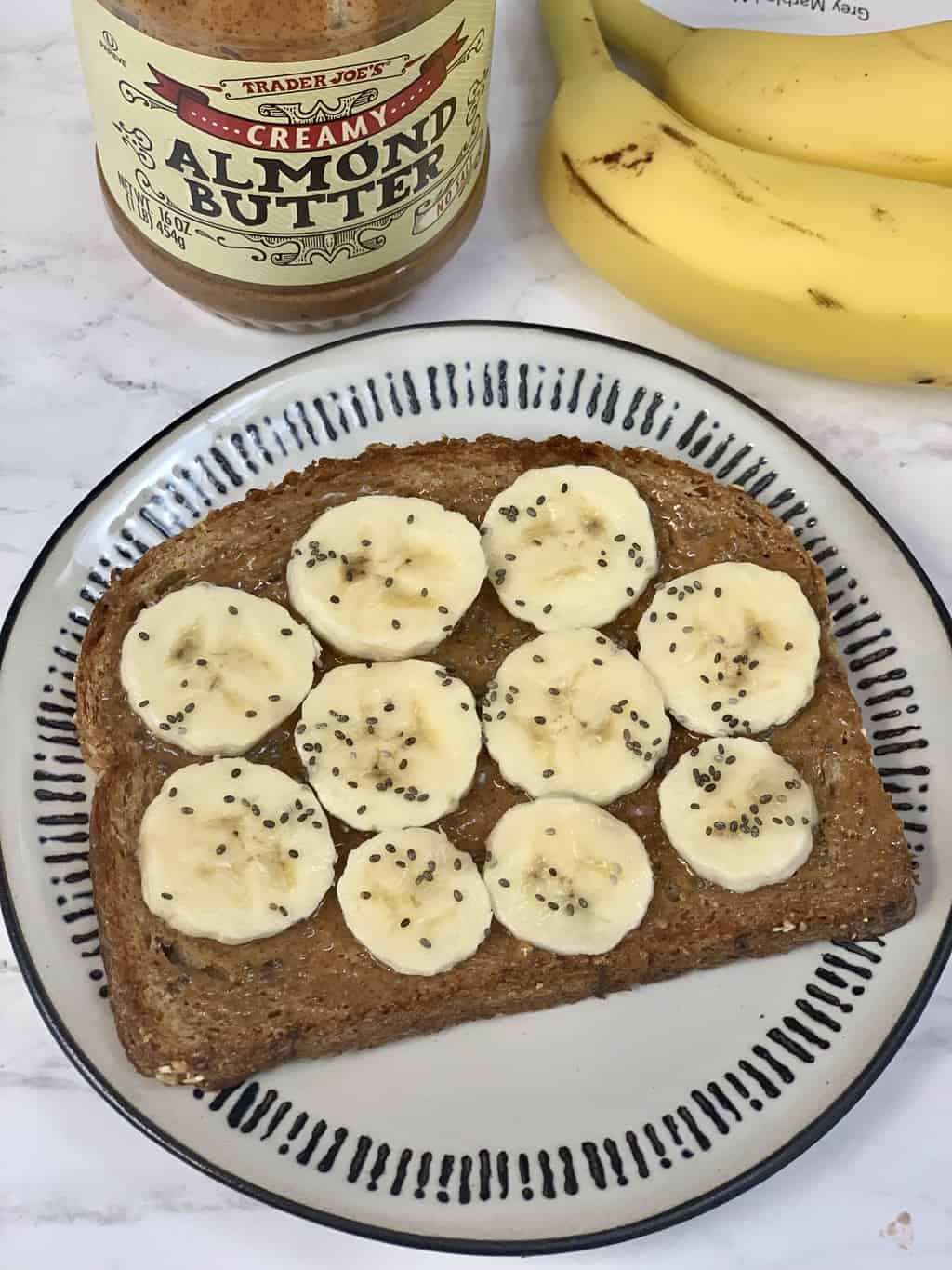 almond butter chia toast served on a plate with sliced banana and chia seeds on the top