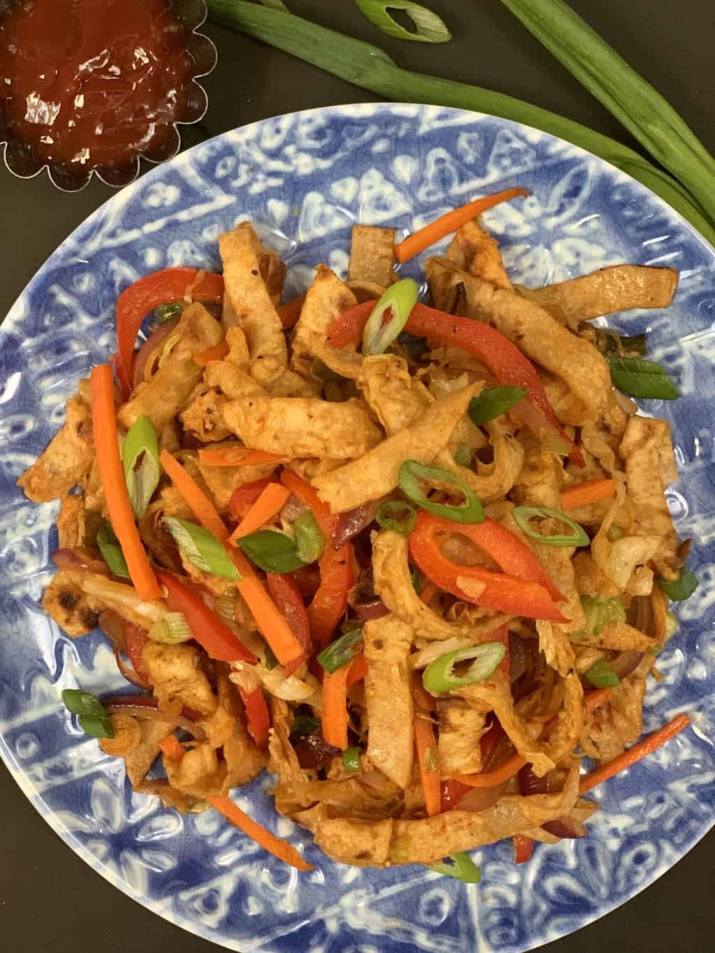 Chapati Noodles served on a plate garnished with spring onions with side of ketchup