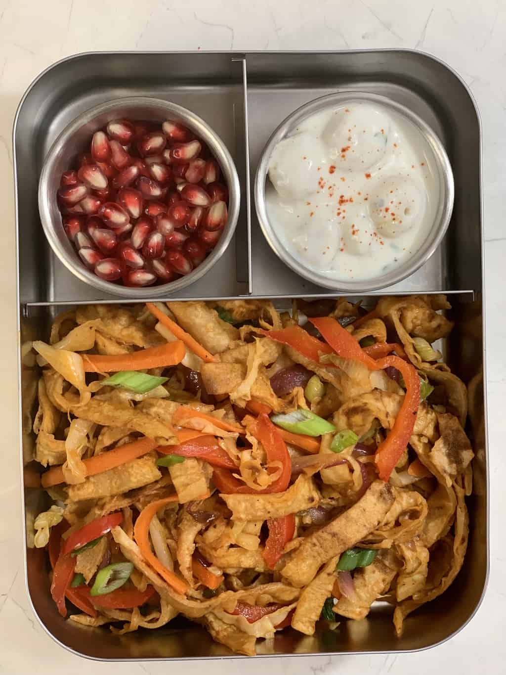 chapati noodles, makhana raita and pomegranate seeds in steel bento lunch box.