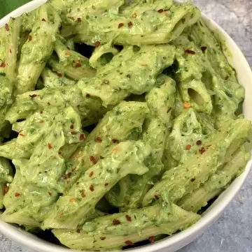 avocado penne pasta served in a white bowl
