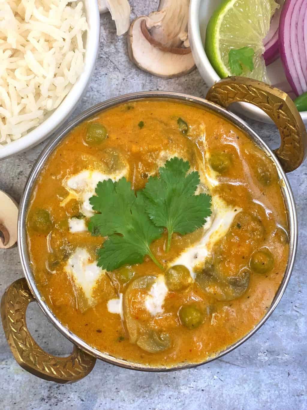 mushroom matar masala served in a kadai topped with vegan cashew cream and coriander leaves