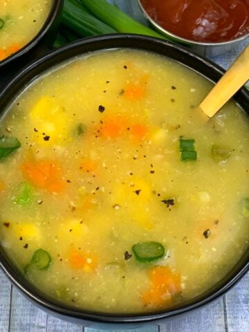 Sweet Corn Soup served in black bowl and ketchup on side