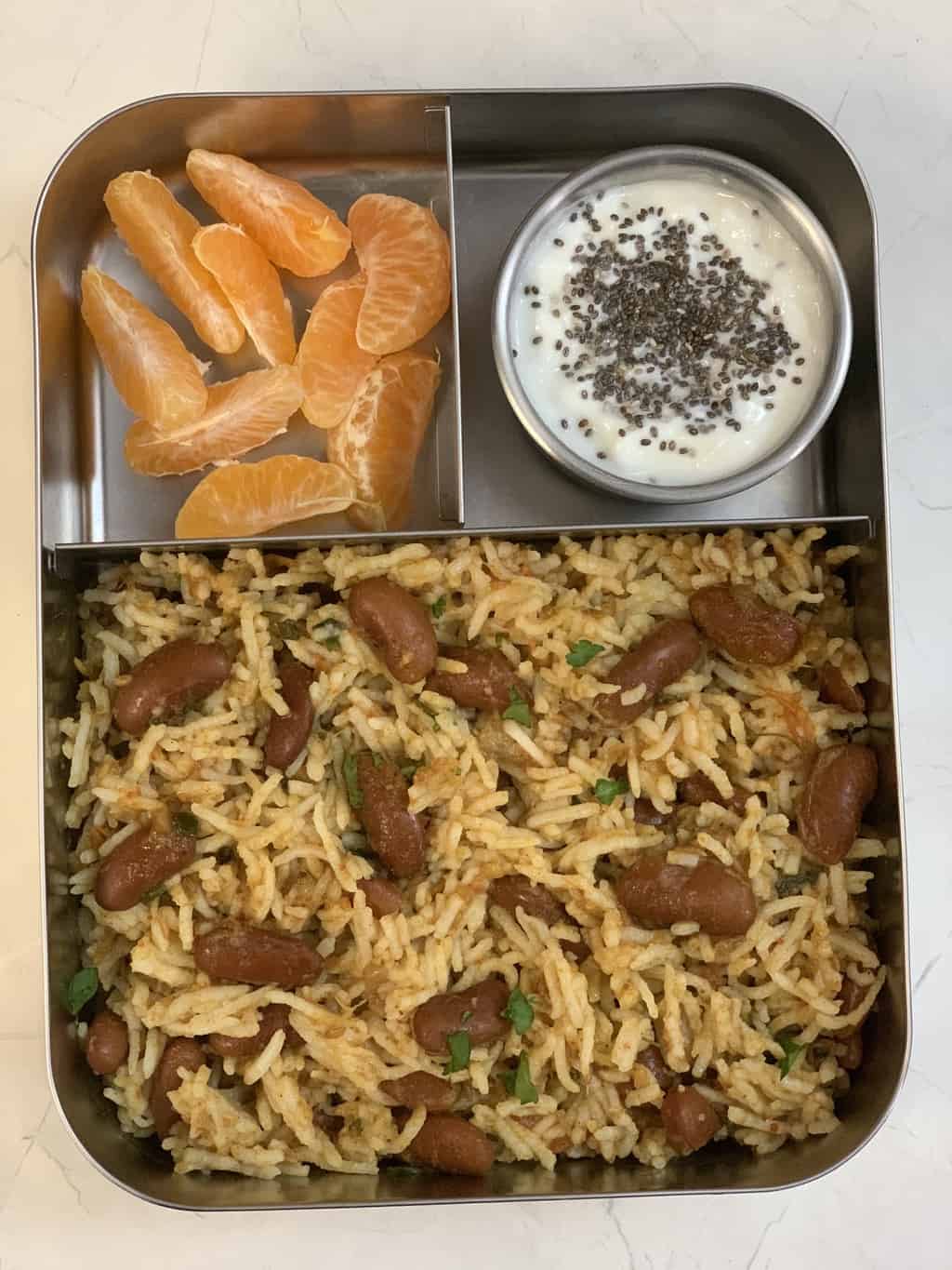 rajma rice served in a kids lunch box with yogurt and orange