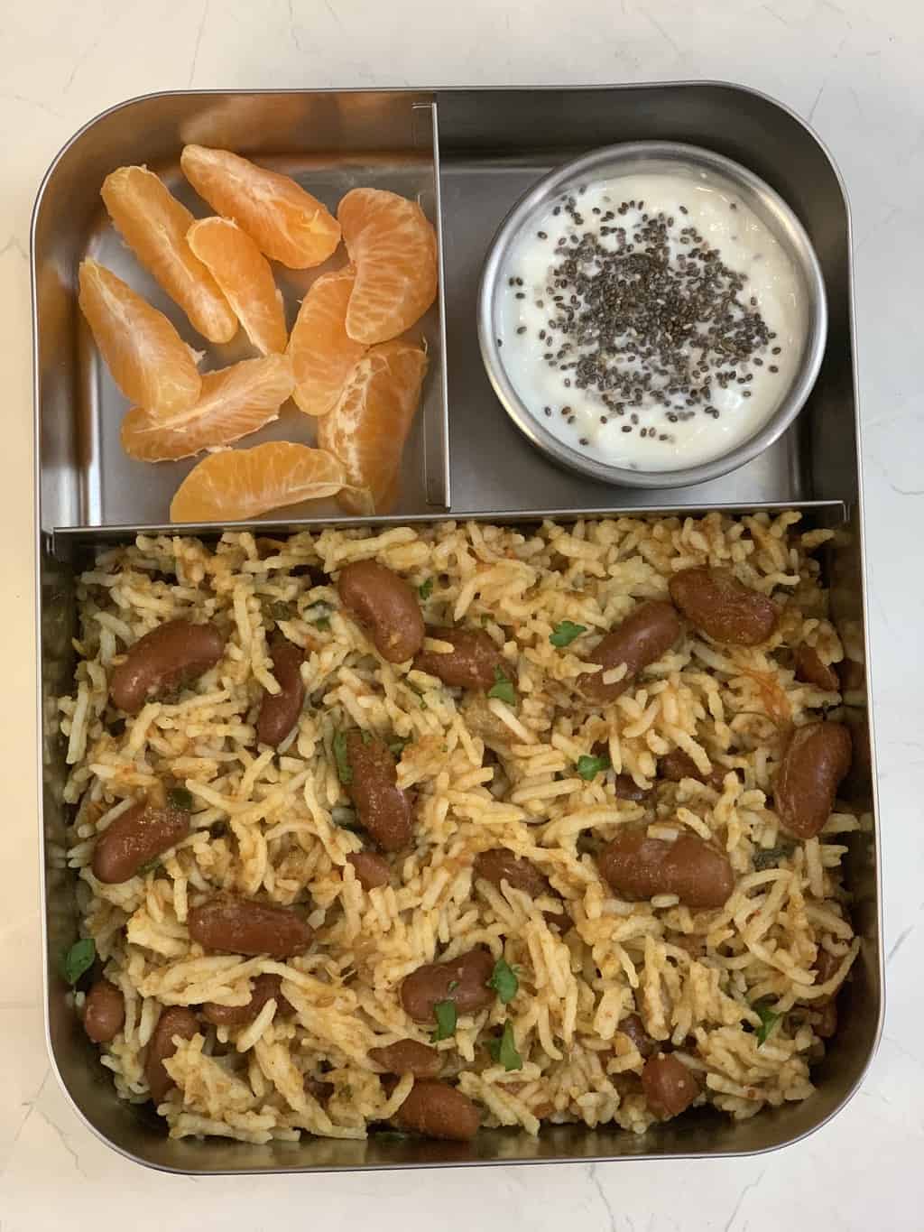 rajma rice served in a kids lunch box with yogurt (with chia seeds) and orange