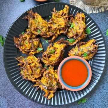 air fryer onion pakoda on the serving plate with tomato ketchup on the side.