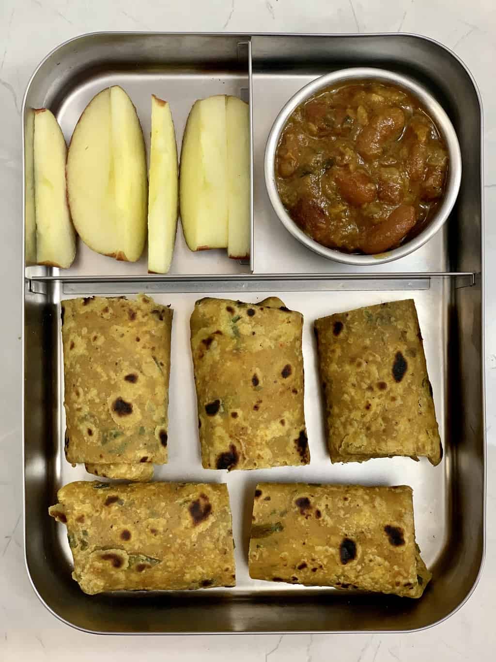 flaxseed paratha with rajma and apple slices in steel bento lunch box