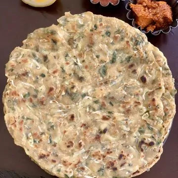 Lauki Paratha podávaná na talíři s citronovou klínovou okurkou na boku