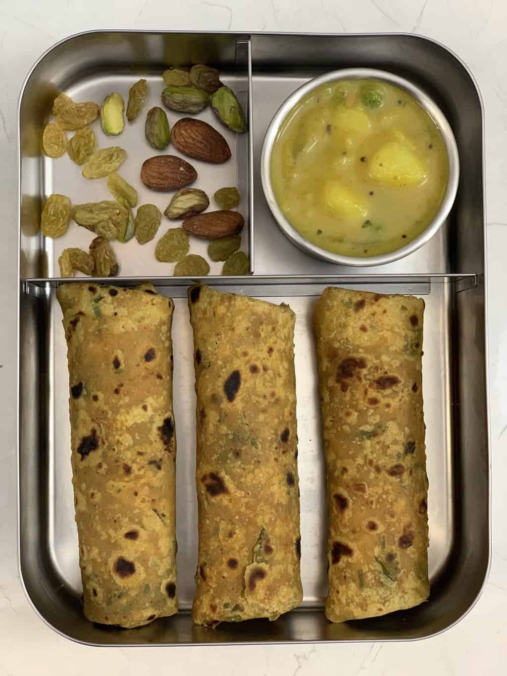 makhana paratha in steel bento lunch box with potato curry and nuts