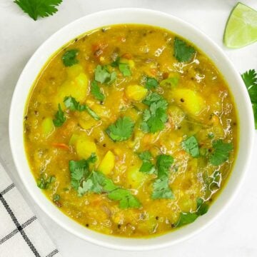 potato sagu/bombay sagu served in a bowl garnished with cilantro and poori on the side