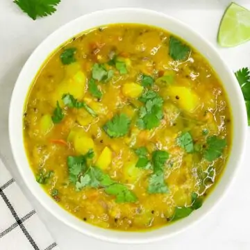 potato sagu/bombay sagu served in a bowl garnished with cilantro and poori on the side
