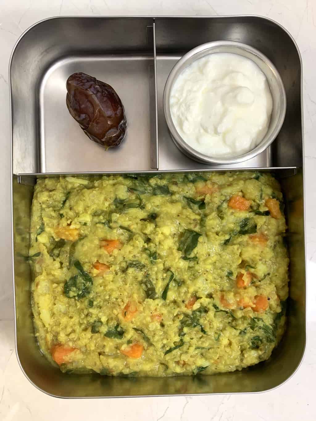 bajre/bajra ki khichdi served in a steel kids lunch box along with yogurt and dates