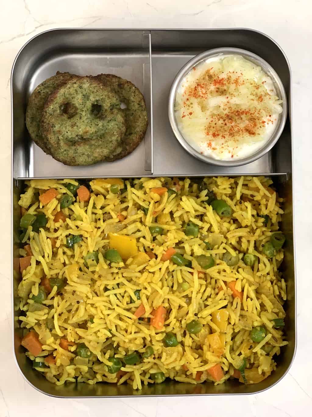 Masala Rice, Lauki Raita and Broccoli Smileys in steel lunch box.