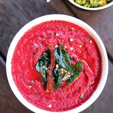 Beetroot chutney served in a bowl with tempering on the top and carrot beans poriyal on the side.