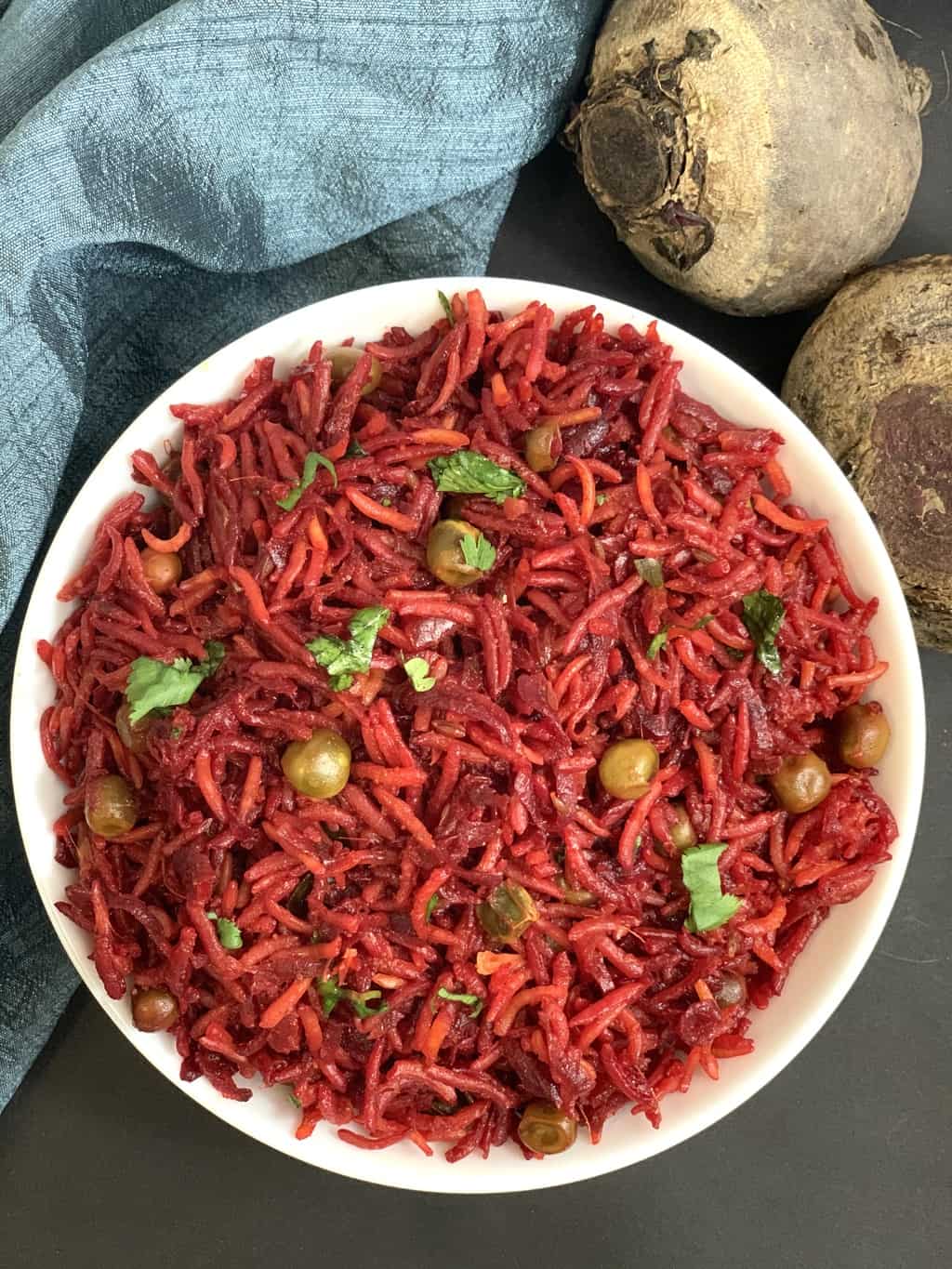 instant pot beetroot pulao served in a bowl garnished with cilantro with raw beets on the side