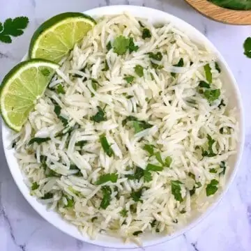Instant pot cilantro lime rice served in a white bowl with lemon wedges on top