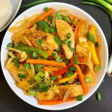 Vegetable Fried Idli served in a bow garnished with green onions