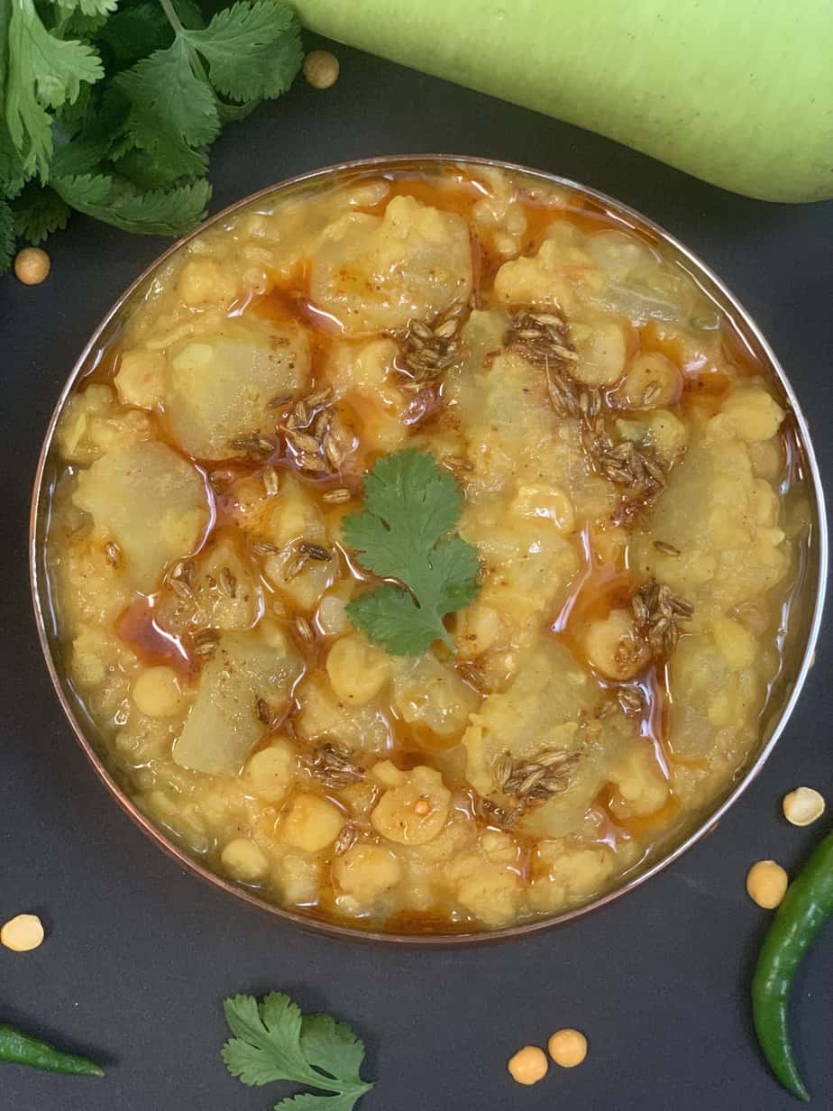 lauki chana dal cooked in instant pot served in a vessel with tempering on the top and cilantro and whole lauki on the side