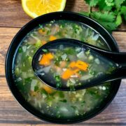 lemon coriander soup recipe served in a black bowl and lemon on side