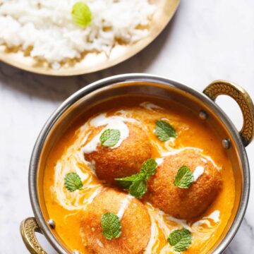 Malai kofta served in a kadai with rice on the side.