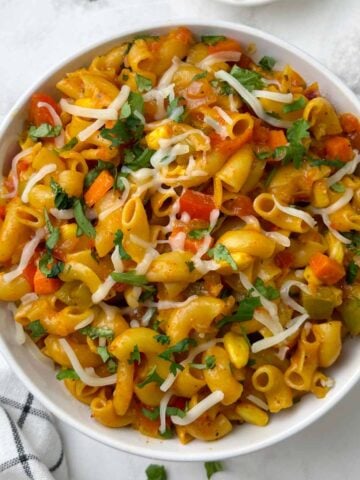 masala macaroni pasta served in a bowl with cheese on the side