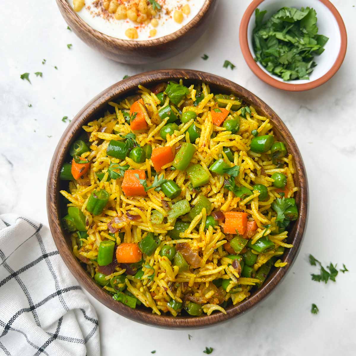 Masala Rice served in a bowl with boondi raita and cilantro on the side