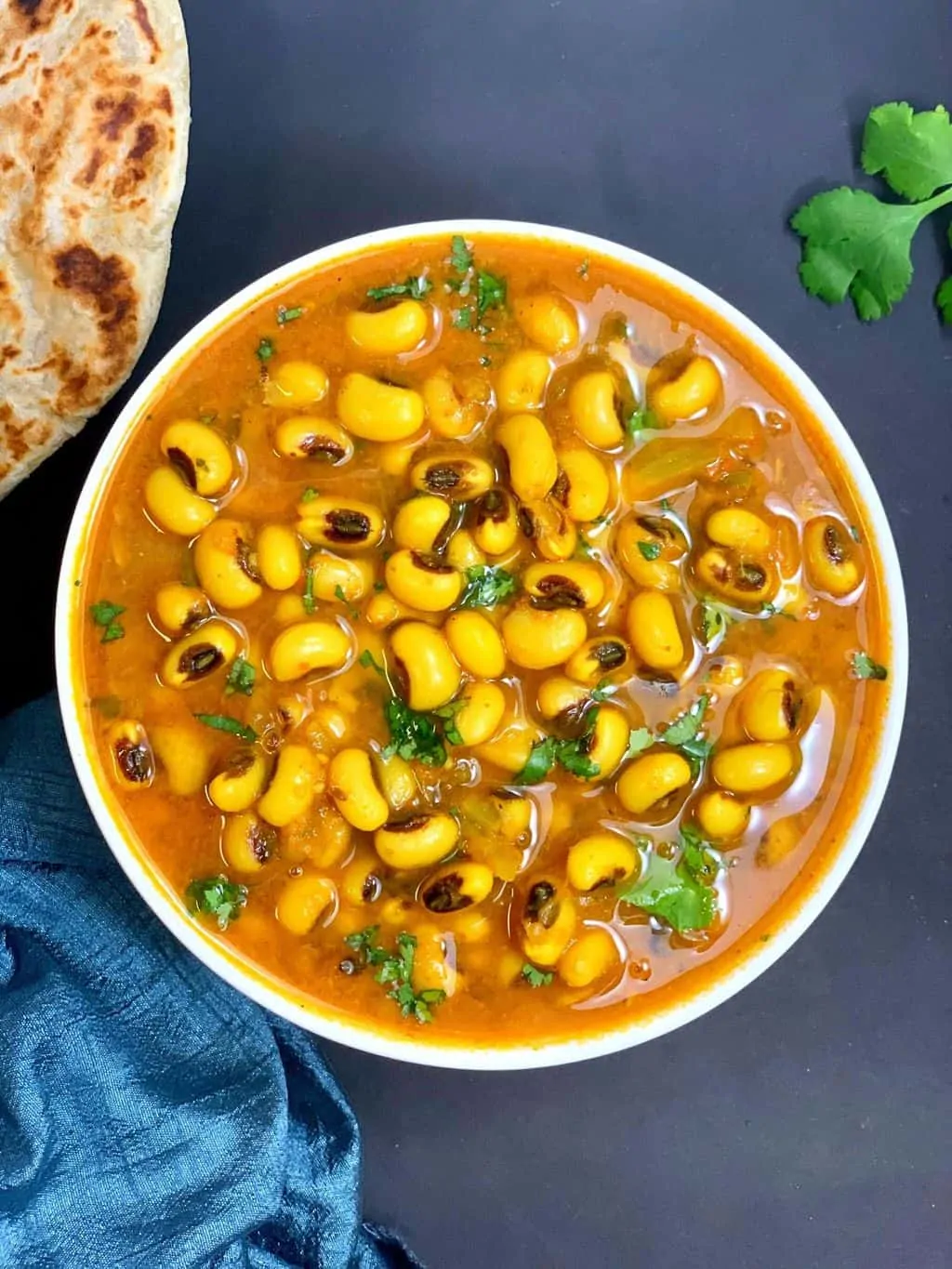 black eyed pea curry (indian lobia masala) made in the instant pot pressure cooker served in a white bowl with paratha on side