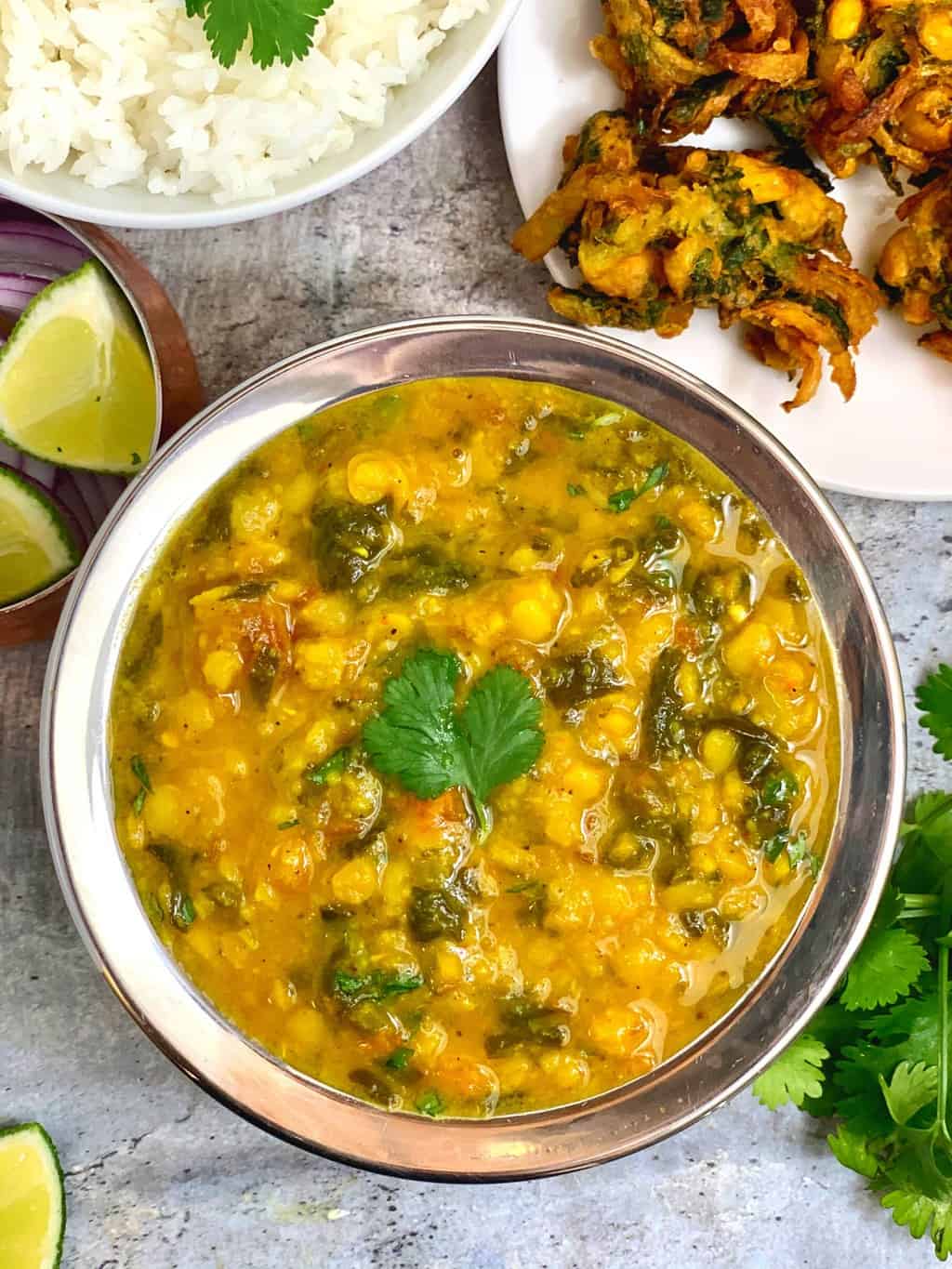Spinach Dal served in a bowl with steamed rice and pakoda on the side