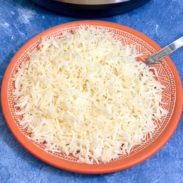 perfect basmati rice served in a plate with a fork with instant pot on the side