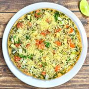 khakra chaat served on a plate with sev and toppings on top with lemon wedge on the side