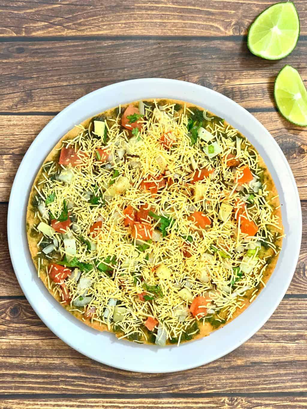 khakra chaat recipe served on a plate with sev and tomato on the top t