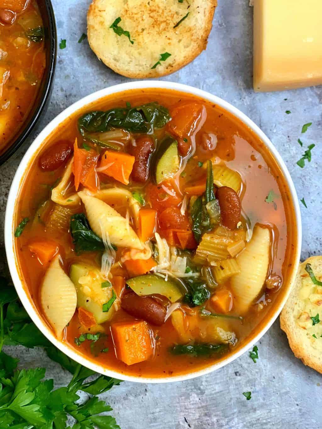 minestrone soup served in a bowl with crusty bread on the side