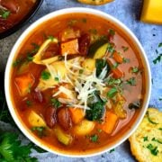 olive garden minestrone soup served in a white bowl with parmesan cheese on top and garlic bread ,parsley on side