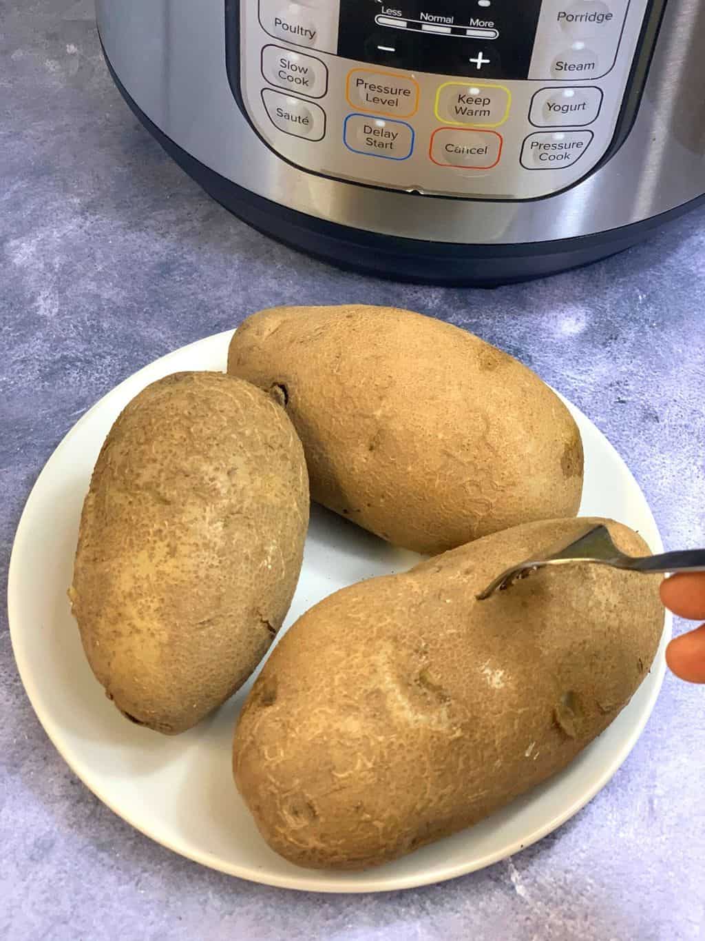 boil russet potatoes on a plate with a fork and instant pot on the side