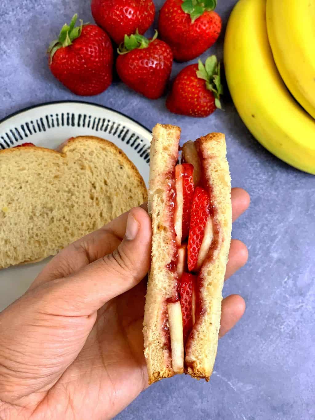 fruit sandwich cut in to half with fruits on the side