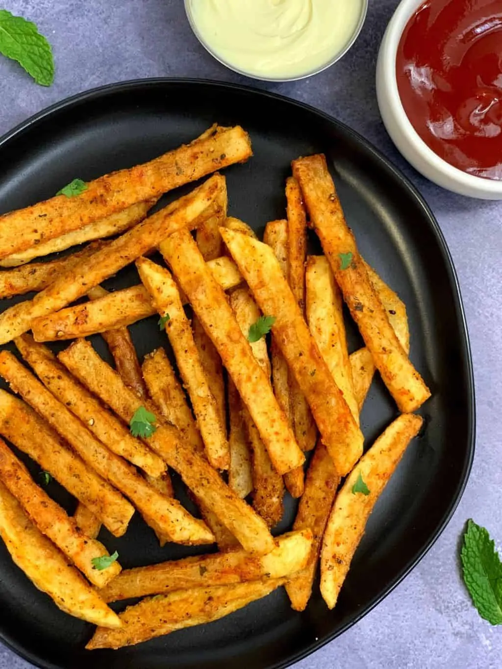 masala french fries served in a plate with tomato ketchup and mayonnaise on the side