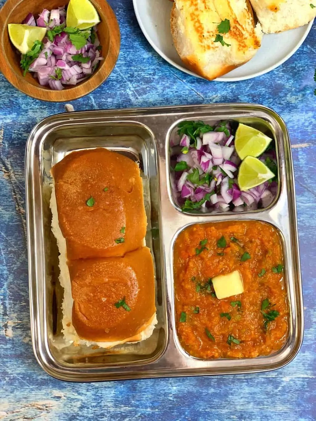 pav bhaji served in a plate with pav and onions and lemon wedges
