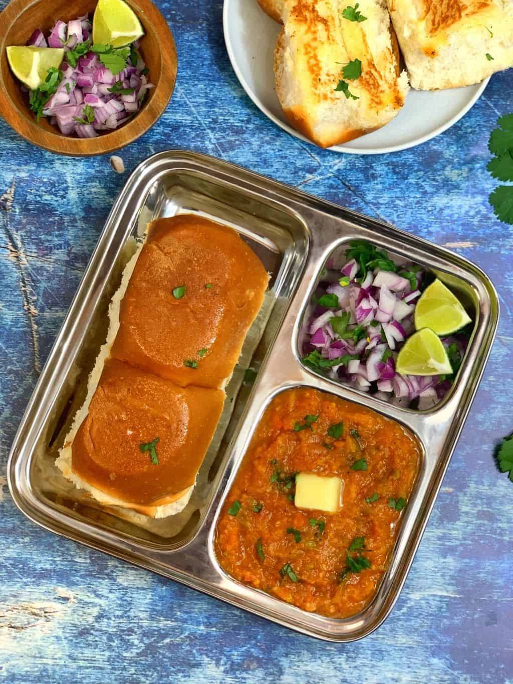 instant pot pav bhaji served in a plate with toasted buns and cilantro and lemon