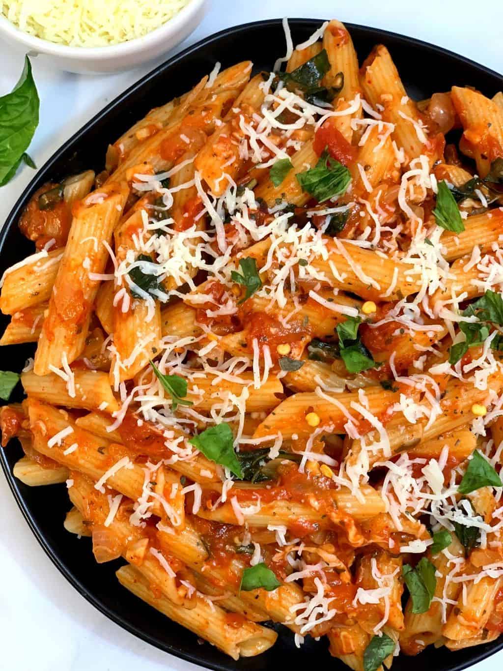 tomato basil pasta served in a plate garnished with mozzarella cheese