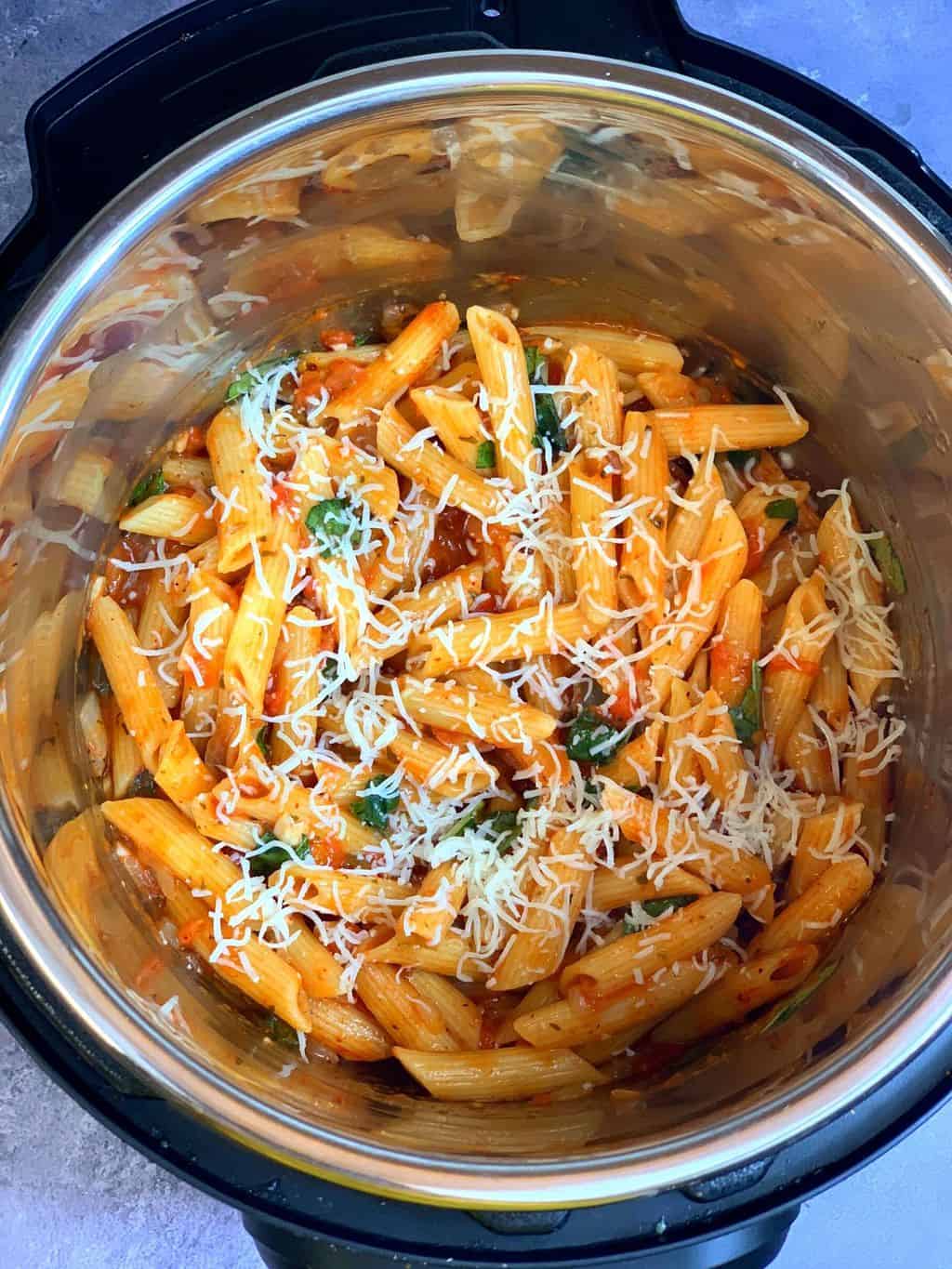 tomato basil pasta in instant pot insert garnished with basil leaves