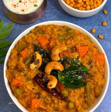 Instant Pot Bisibelebath/bisi bele bath recipe served in a white bowl ,boondi and raita on side