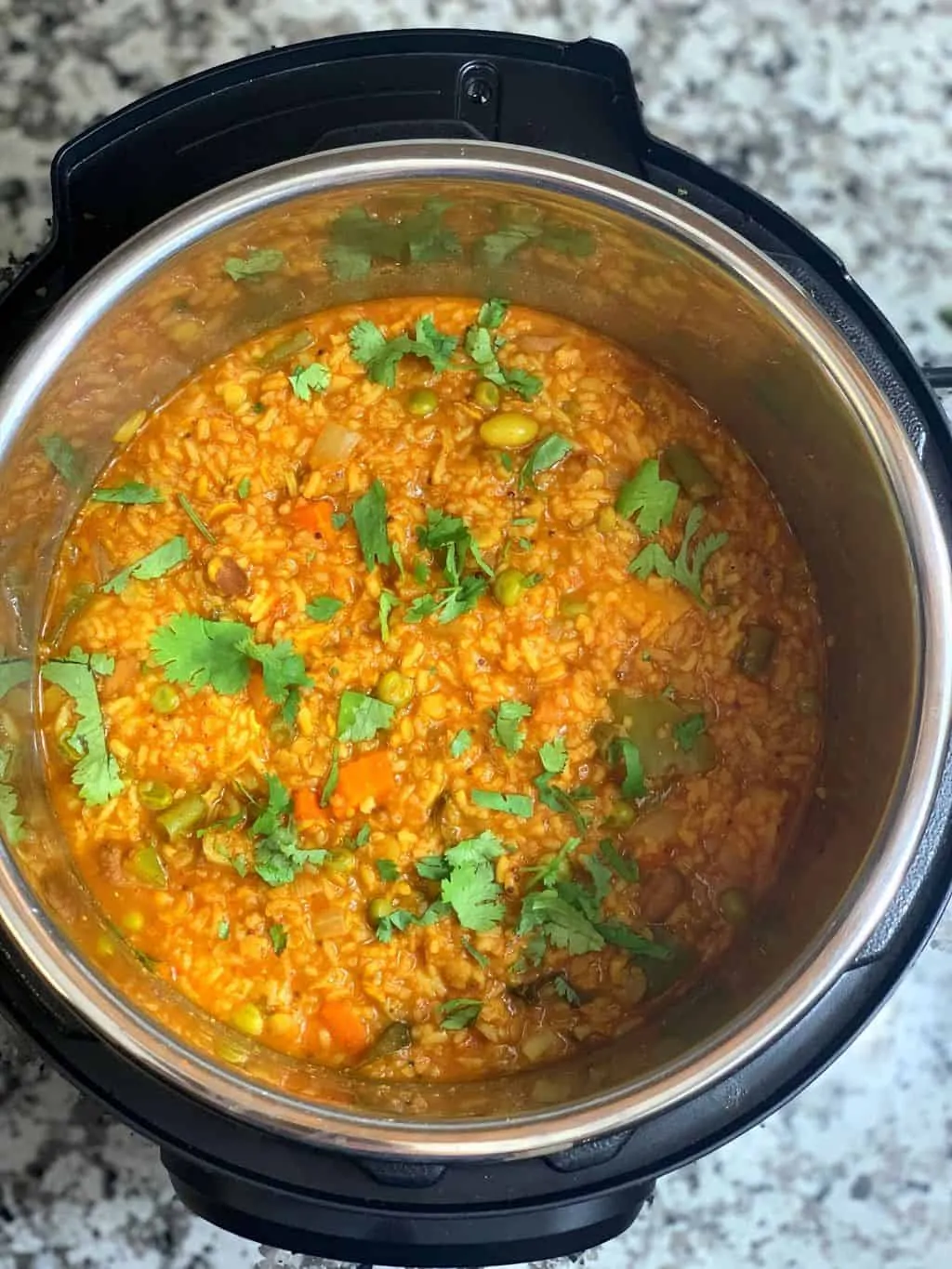 bisi bele bath in instant pot insert garnished with coriander leaves