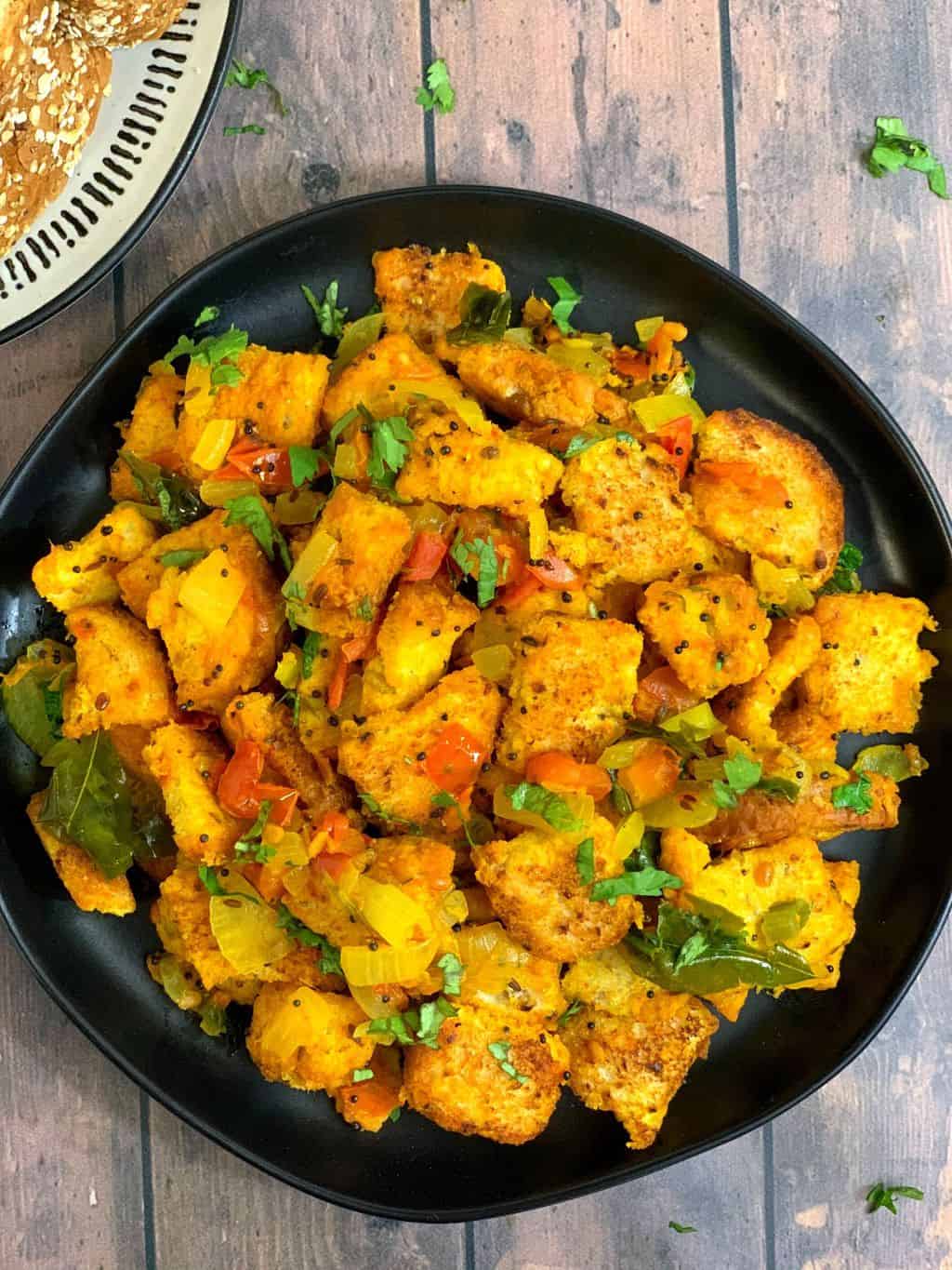 bread upma served in a black plate garnished with cilantro