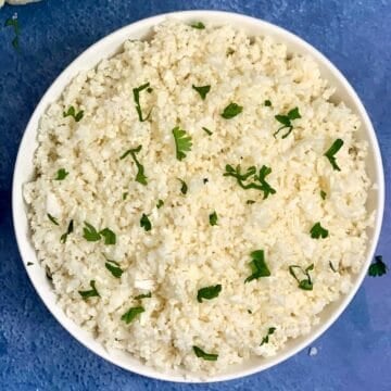 cauliflower rice served in a white bowl garnished with cilantro