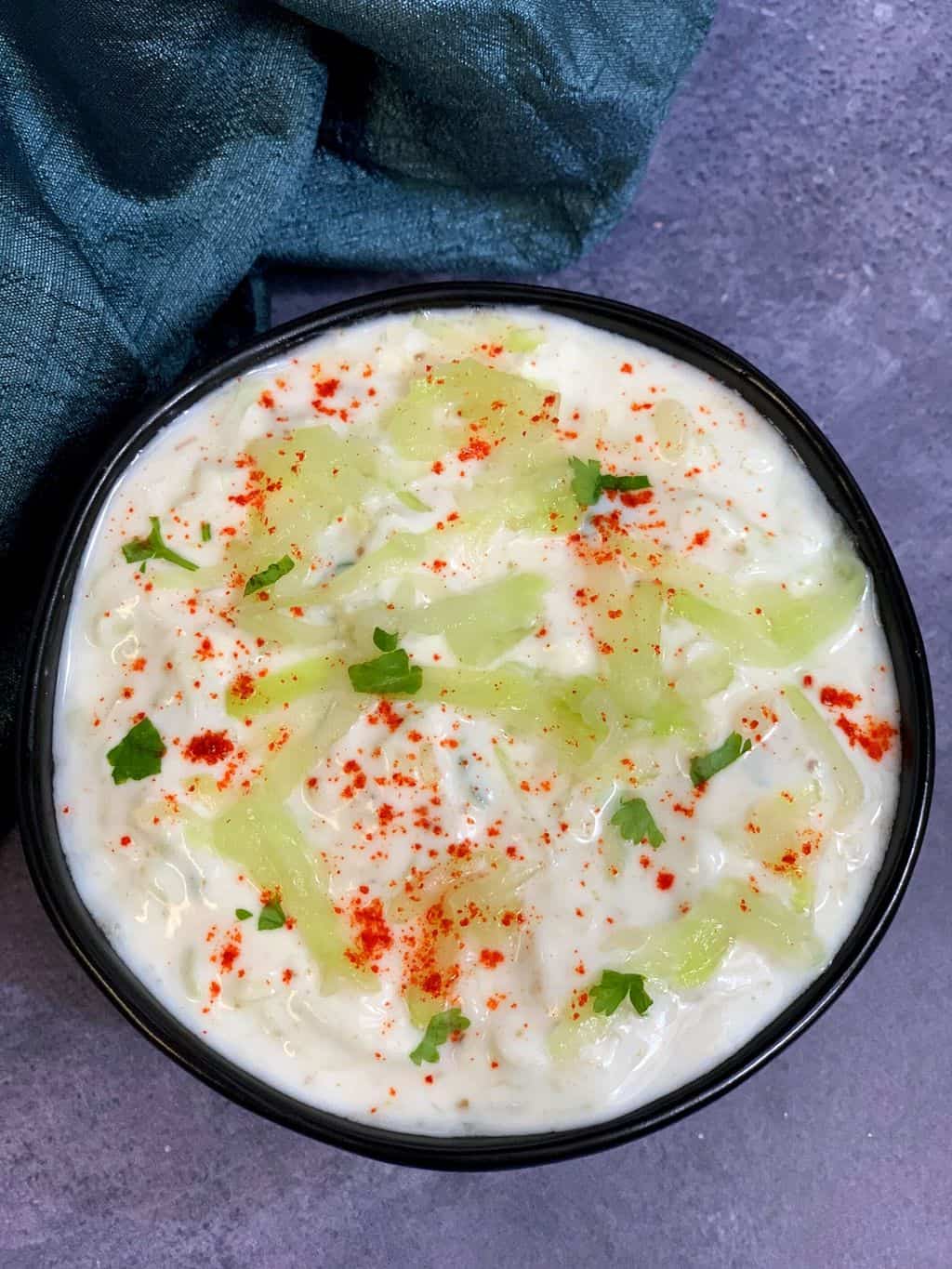 lauki raita served in a bowl garnished with chilli powder coriander and cooked bottle gourd