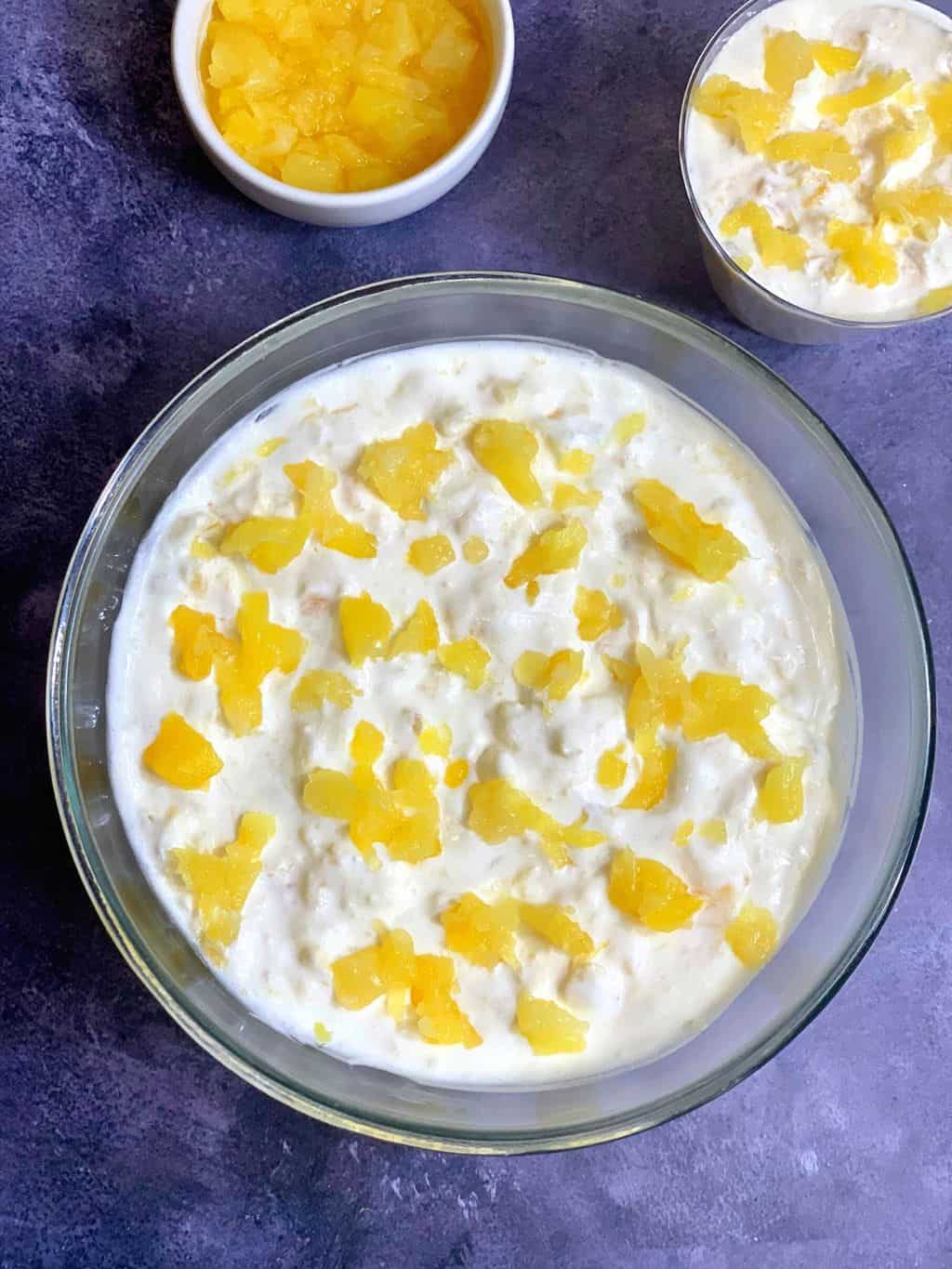 easy Pineapple Dessert served in a glass bowl with spoon on top and canned pineapple on the side