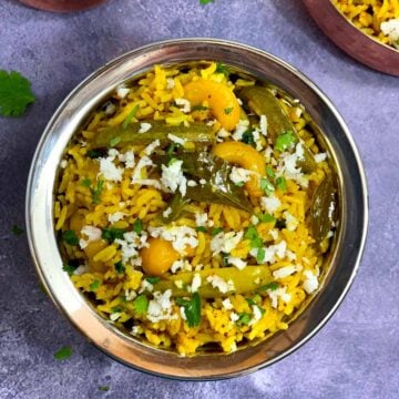 Tendli Masale bhaat served in a steel bowl garnished with cilantro and fresh coconut