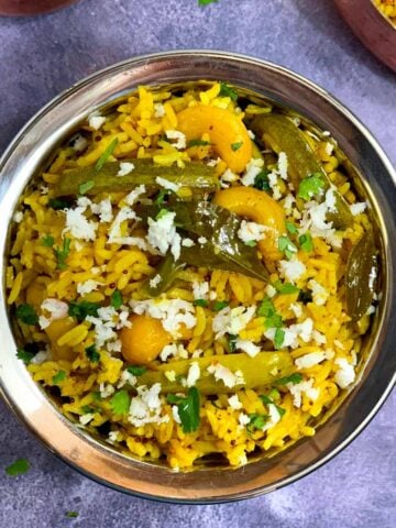 Tendli Masale bhaat served in a steel bowl garnished with cilantro and fresh coconut